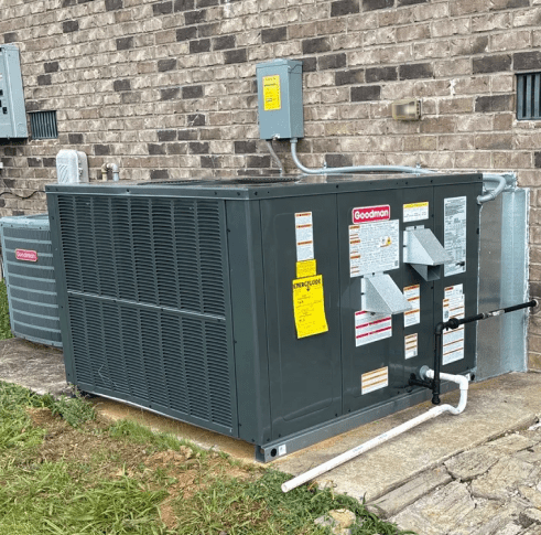 Outdoor HVAC unit beside brick building.